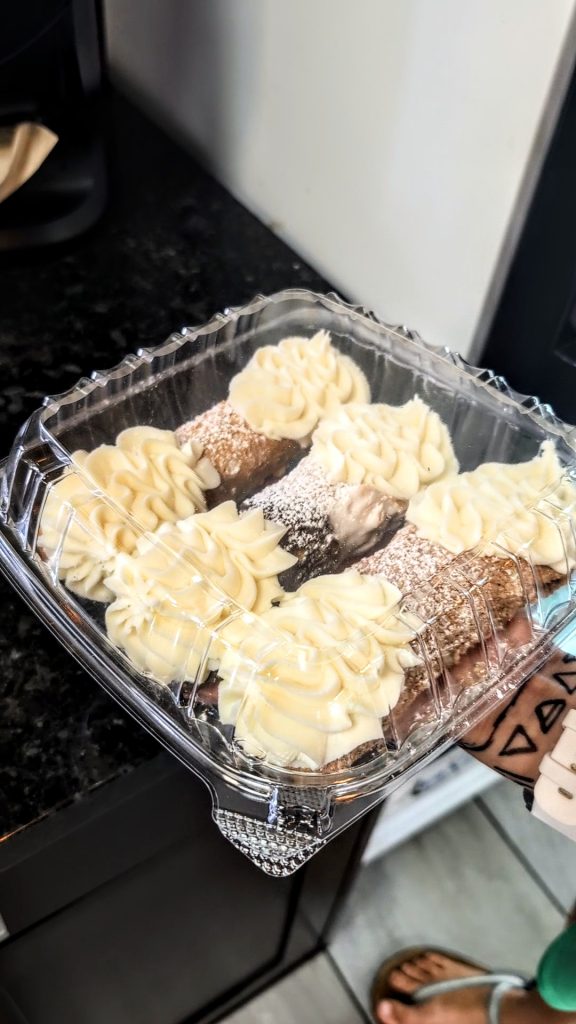 Box of assorted cannoli from Cafe Creme King Cannoli in South Philly, filled with cream and dusted with powdered sugar.